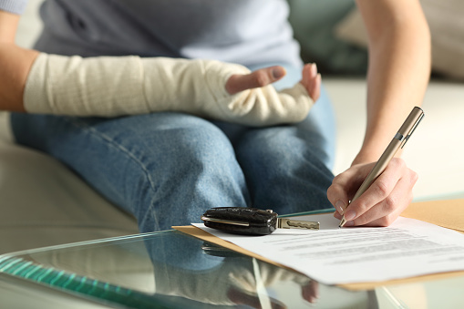 Close up of women with a broken arm signing an important document after a car accident