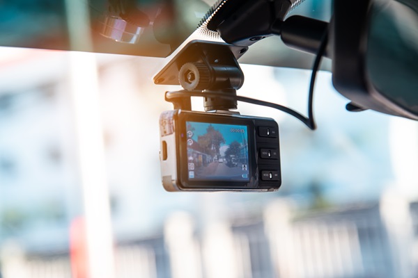 Mounted dashboard camera recording through a car windshield, capturing road footage that may be used as evidence in a car accident or legal investigation.